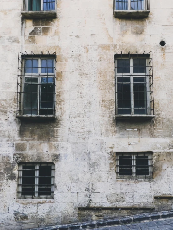 several windows with bars hanging down from them on a building