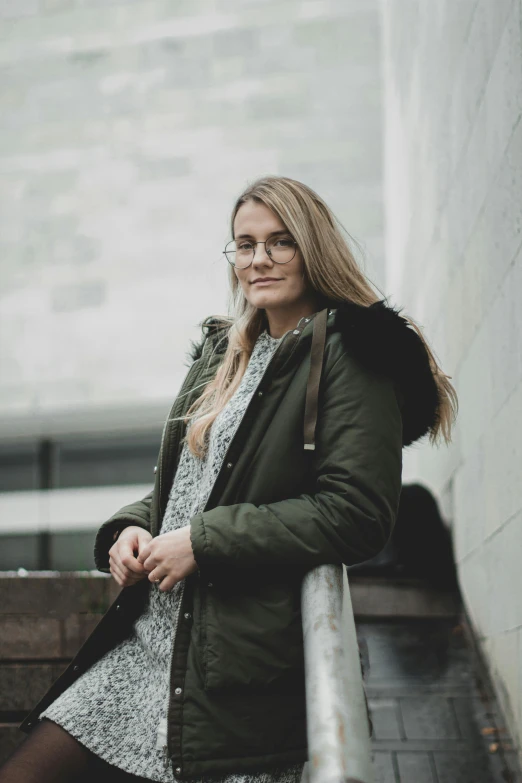 woman standing by concrete wall and looking at the camera