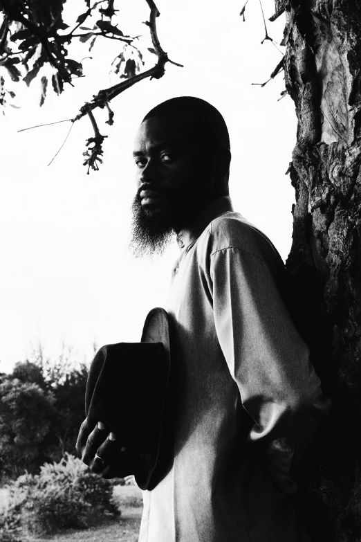 a man with long hair and beard wearing a top hat in front of a tree