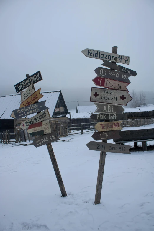 multiple street signs are covered in snow outside