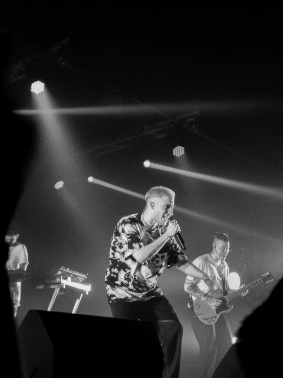 three musicians performing at night on stage with a black and white background