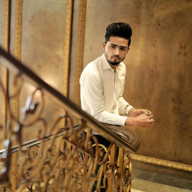 a man wearing a white shirt is standing on a stair rail