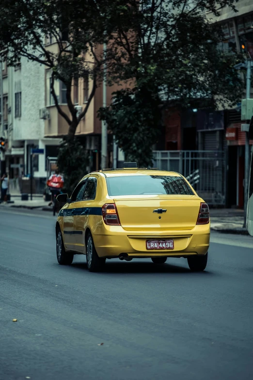 a yellow taxi driving down a street next to tall buildings