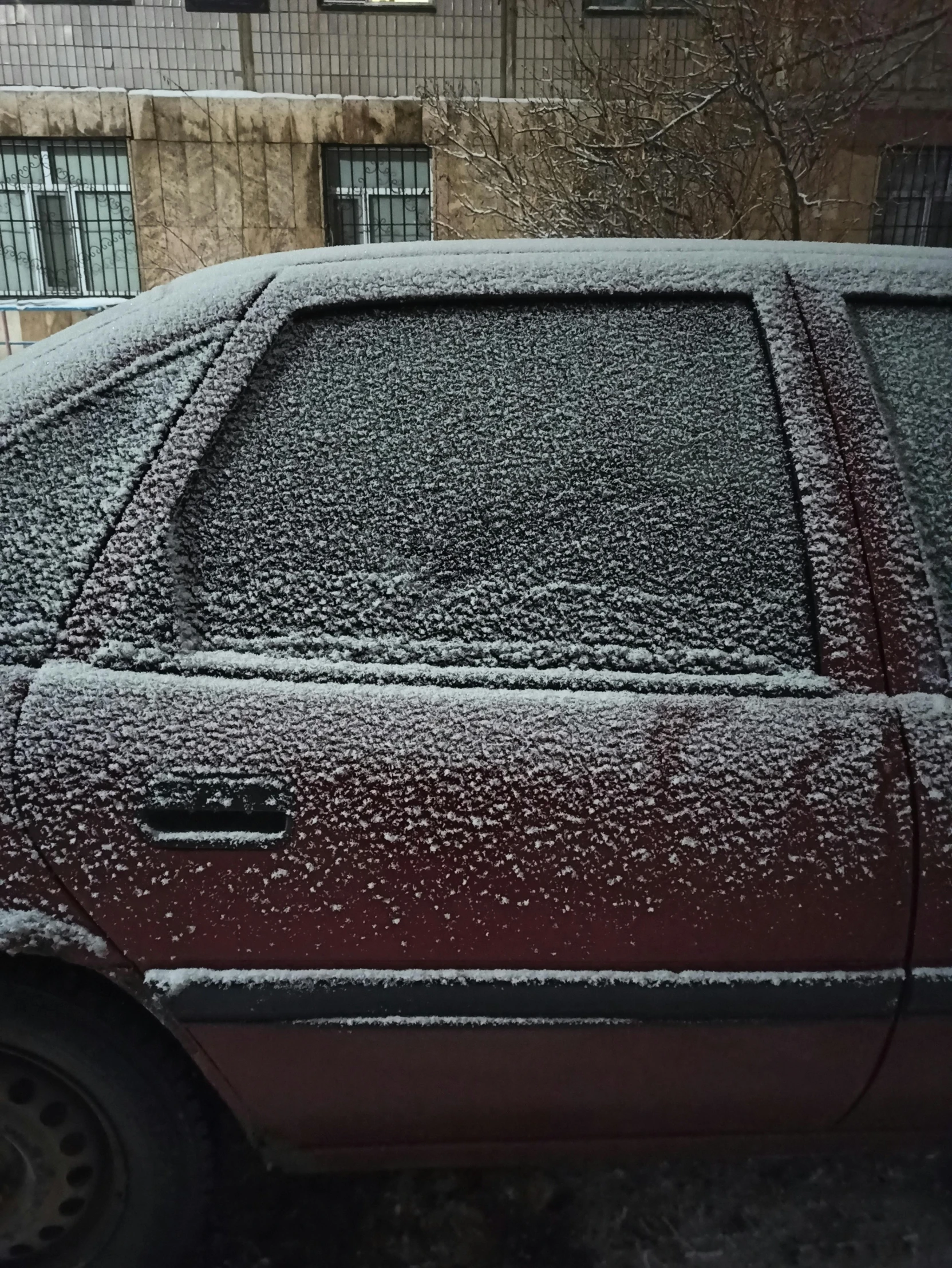 an older car covered in snow parked on the side of the street