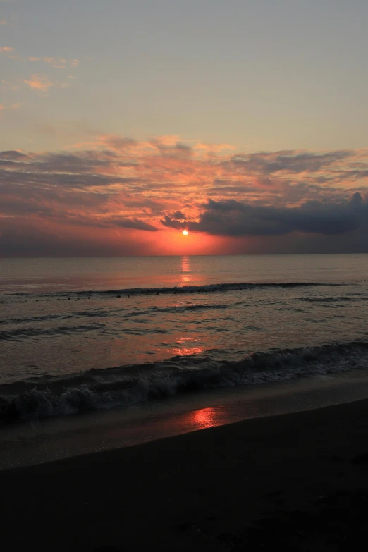 sunset over the ocean at a beach with waves