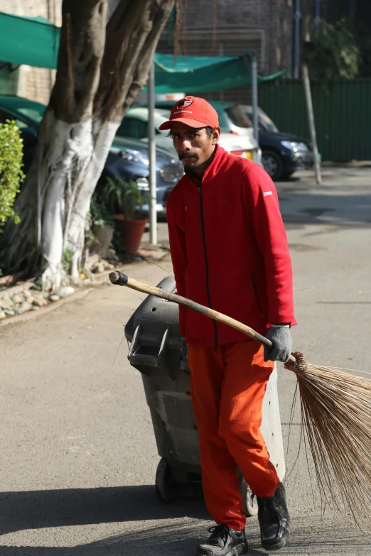 a man sweeping a garbage can with a broom