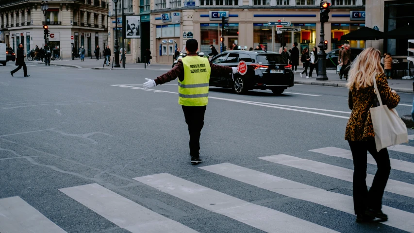 two people cross the street as an emergency officer directs them