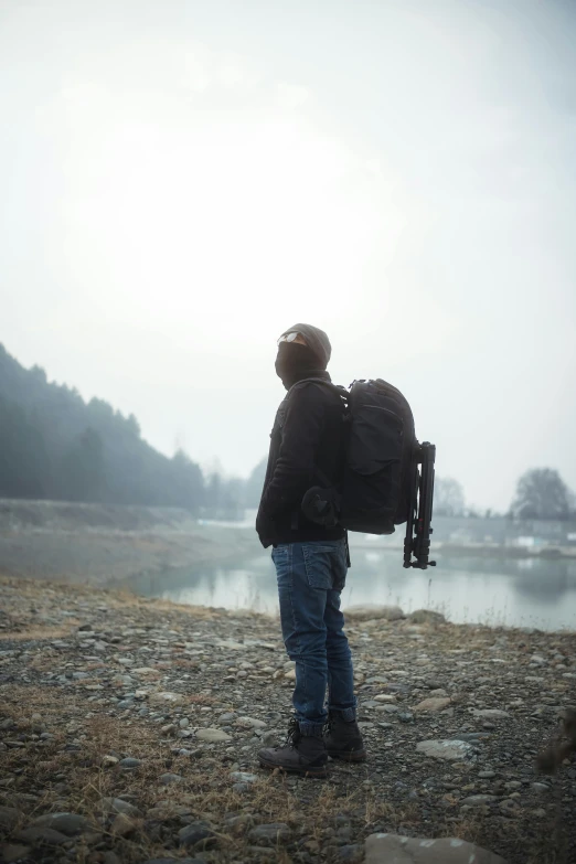 man wearing black jacket and holding camera in fog