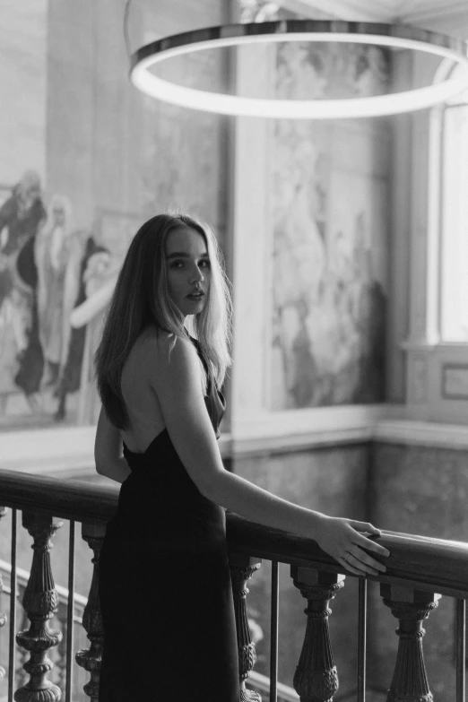 the girl is standing on a balcony with her hands on the railing