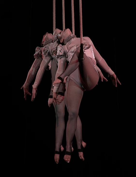 three people on tlfoil suspended from strings on black background