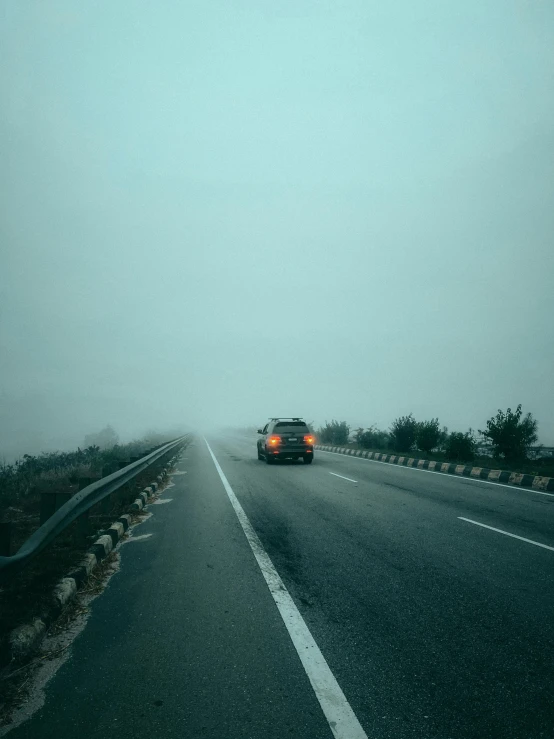 a car is driving down a highway in the mist
