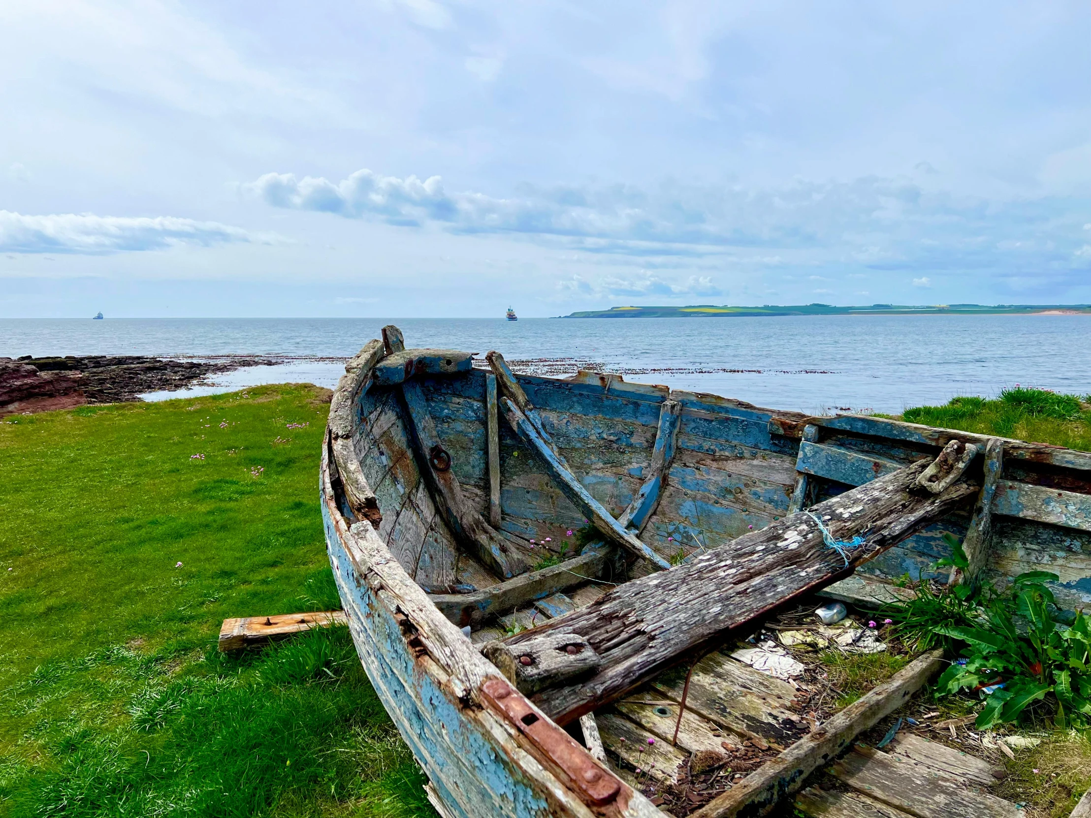 an old wooden boat that has been sitting on some grass