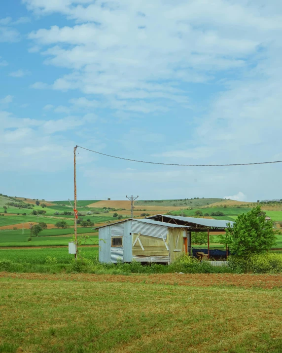 a farm is surrounded by green hills and grass