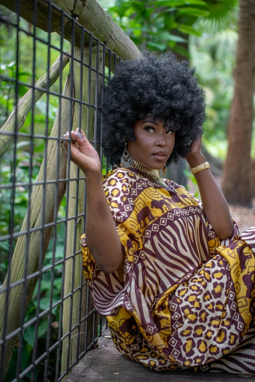 a woman sitting on the ground next to a fence