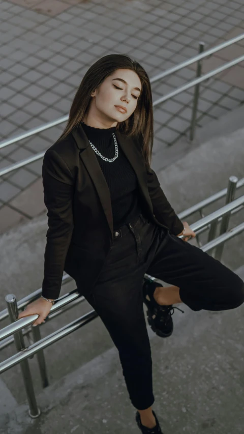 the young woman is wearing a suit, posing on the rail