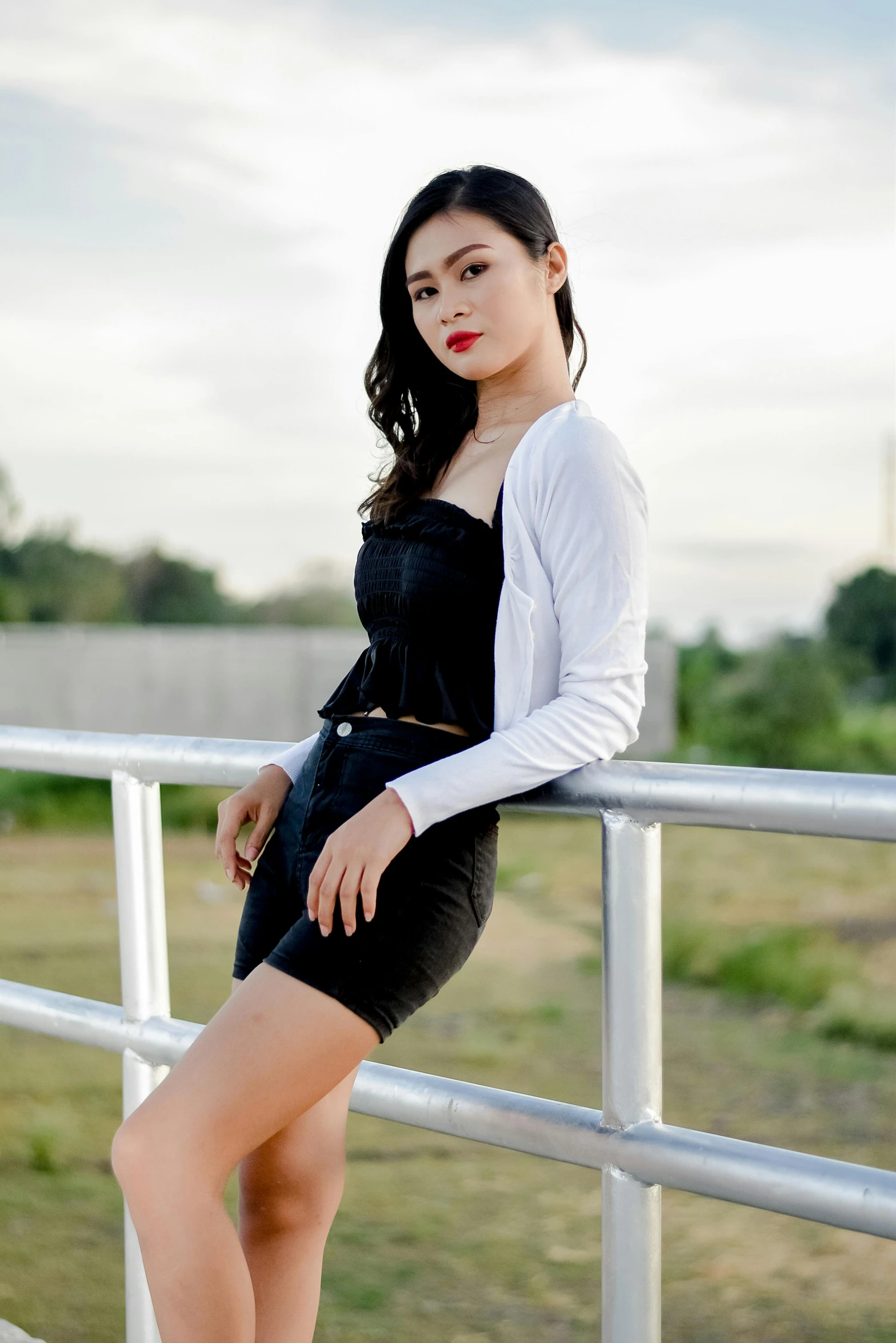 a woman with long hair leaning on a rail posing for the camera