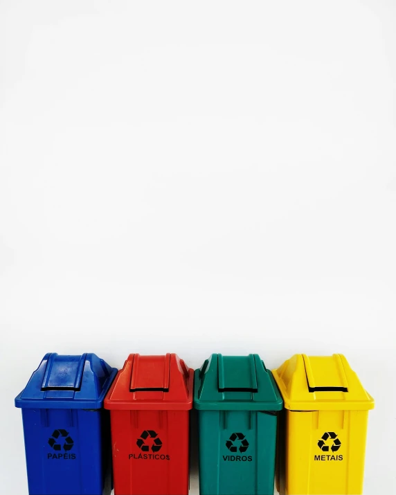 five colorful garbage cans lined up against a white background