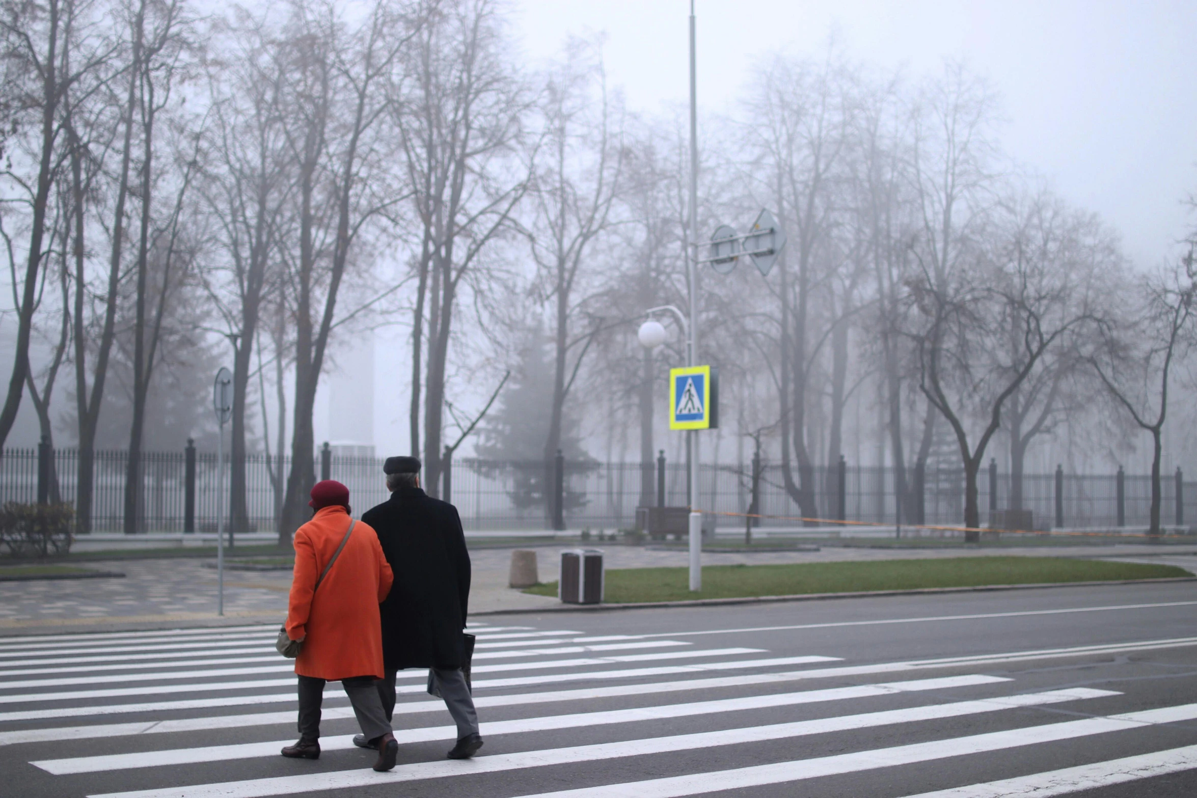 two people are walking down the street in a city on an overcast day