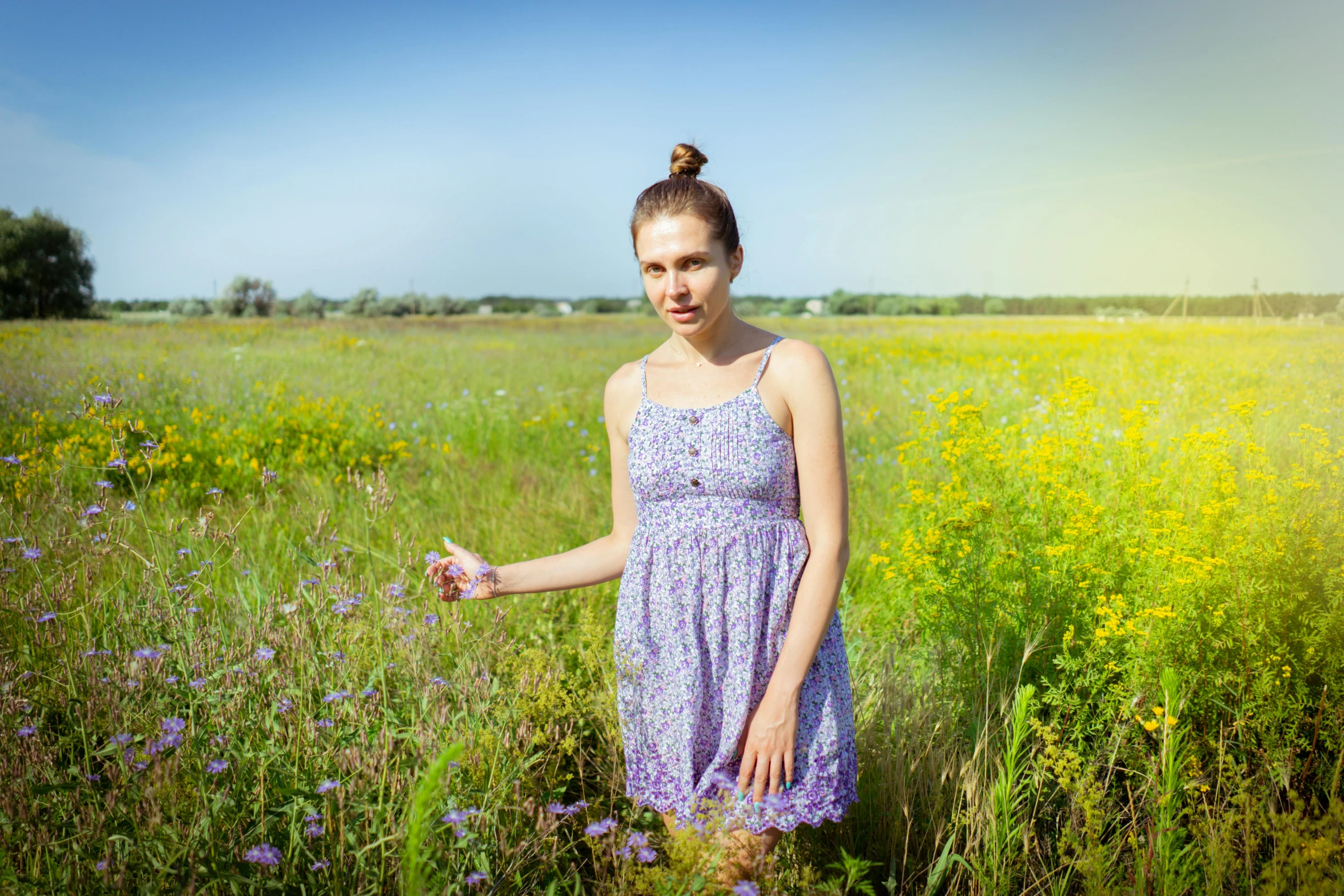 a young woman standing in tall grass near flowers