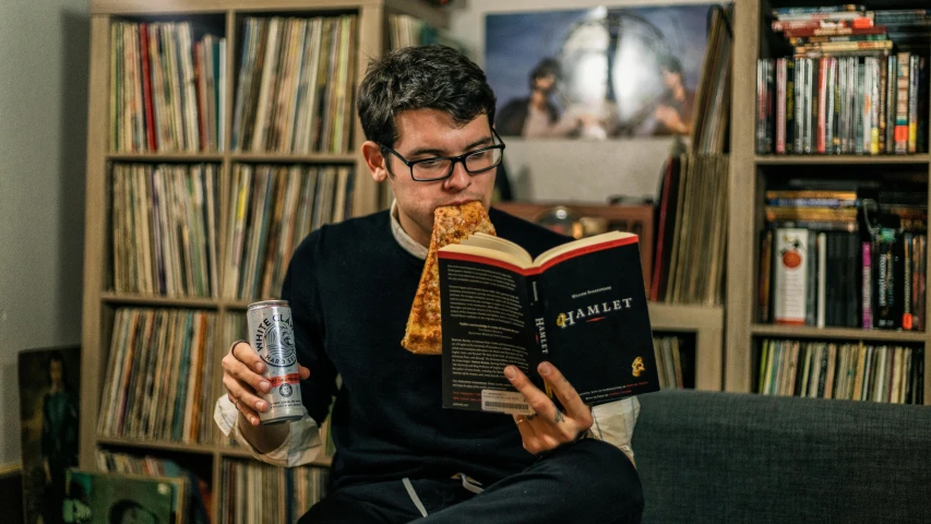 a man reading and reading a book is seen sitting on the couch