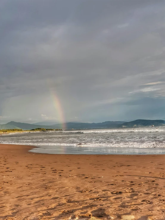 a rainbow in the distance at the beach