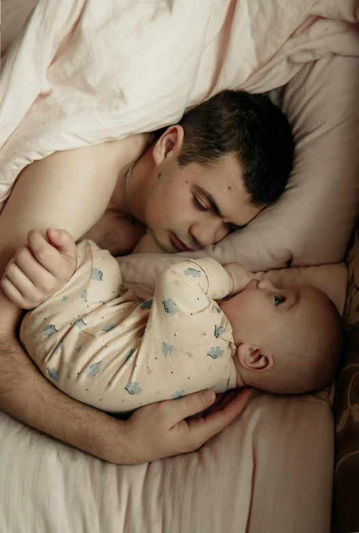 a man sleeping on top of a bed next to a baby