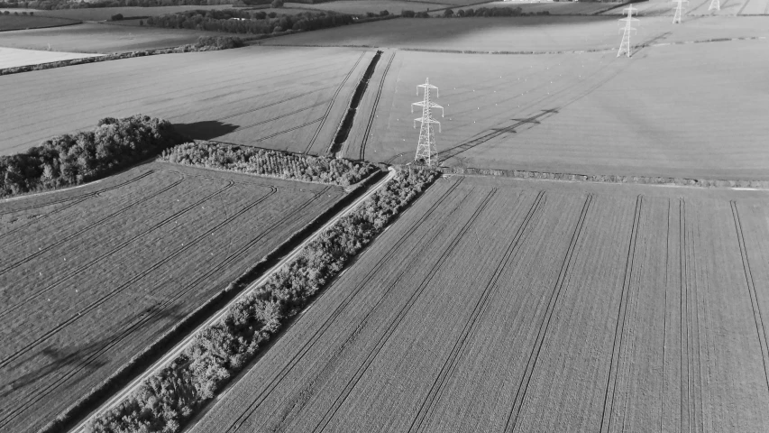 black and white aerial view of farmland landscape and power lines in rural area