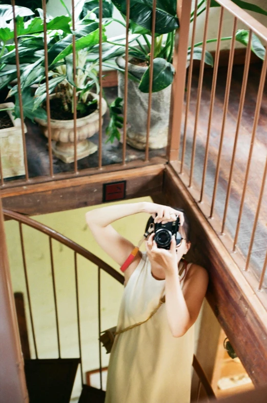 a woman in a dress holding a camera up to her face