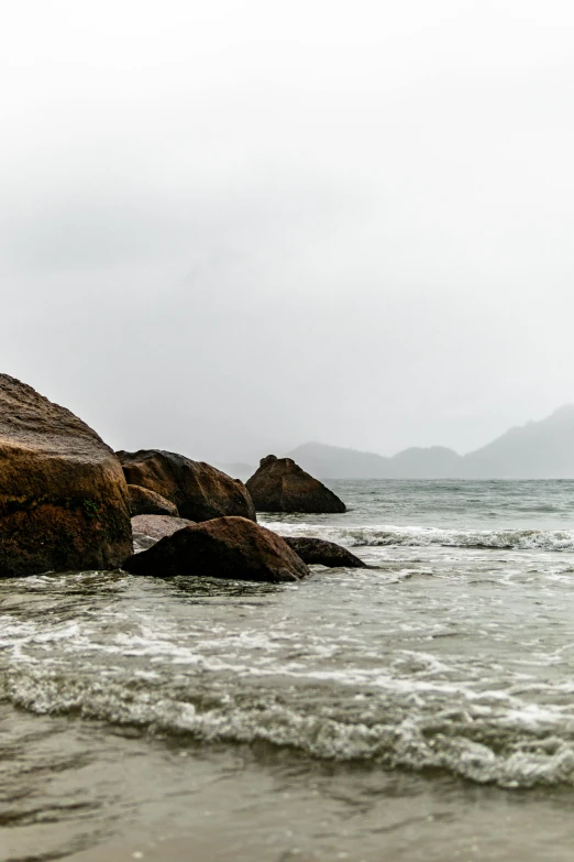 a person standing on the edge of the water next to a rock formation