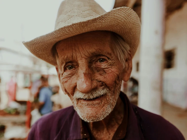 a older man wearing a cowboy hat while standing in the street