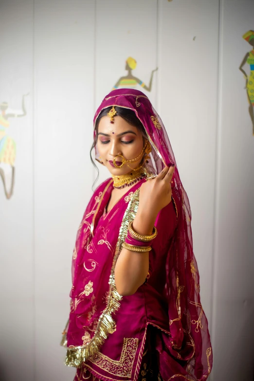 a young woman wearing a maroon sari and gold jewelry