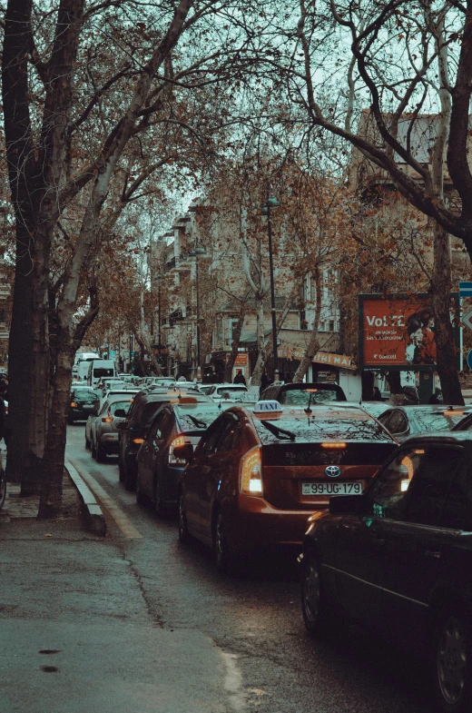 a row of parked cars sitting on a street next to tall buildings