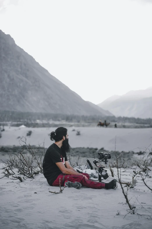 a girl is sitting in the snow while her camera takes a picture