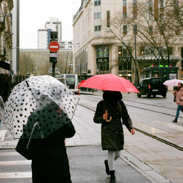 two women holding umbrellas are crossing the street