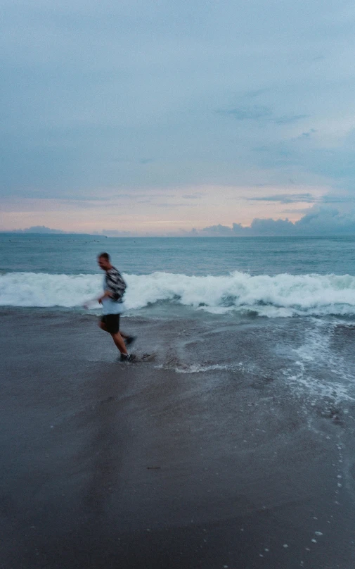 a man is running along the beach near the waves