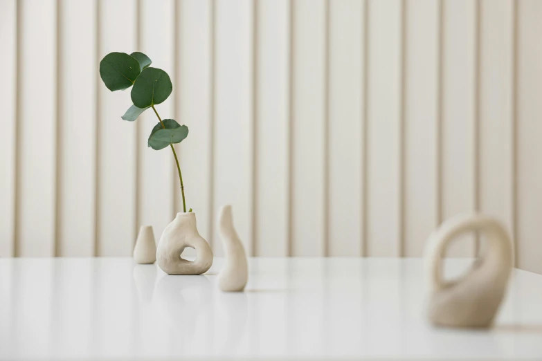 two small white vases holding a plant