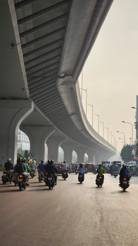 the large group of bikers have stopped on a bridge