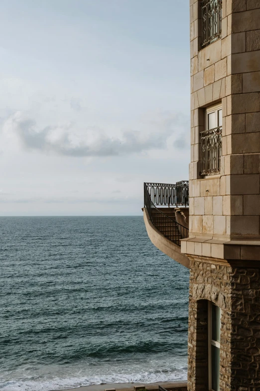 a stone building overlooking the ocean with an open balcony