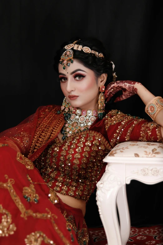 a woman in a red wedding outfit sitting with her hands on her chest