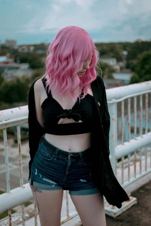 a girl with pink hair and black jacket looks at soing