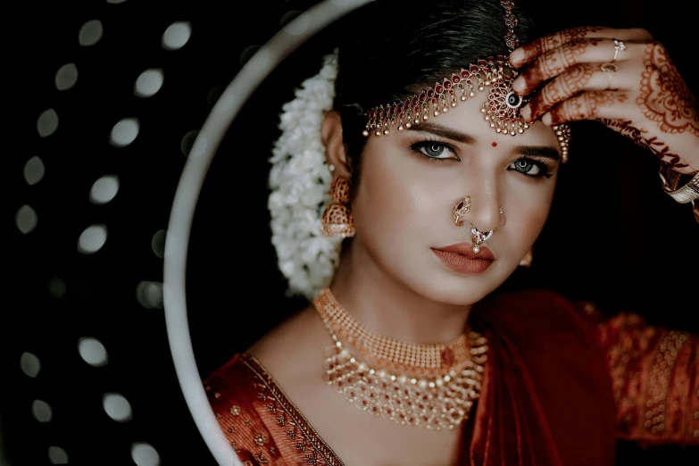 a woman dressed in a traditional indian outfit holding her hand up to her face