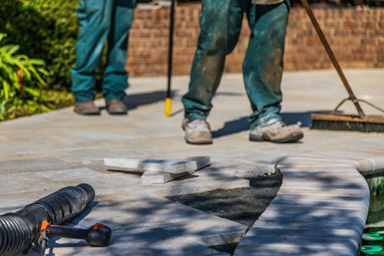 two people on a walkway with tools and a broom