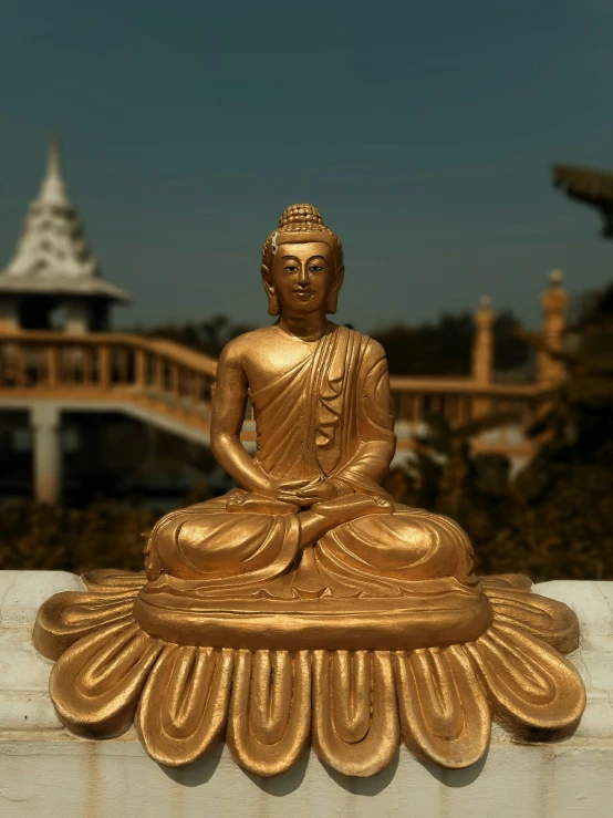 a gold buddha statue sitting on top of a stone block