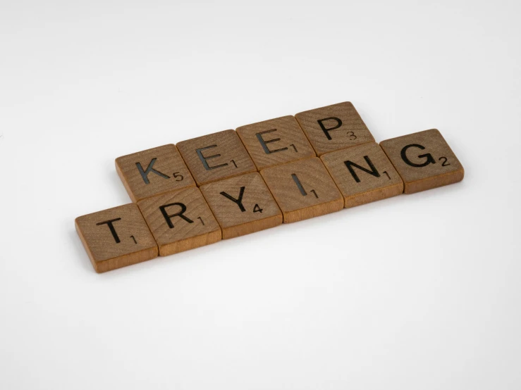 a scrabble tile saying keep trying with letter tiles