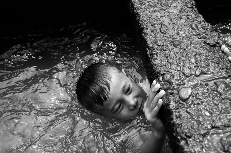 the man is floating in water next to a wooden fence