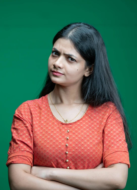 a woman with long black hair wearing an orange shirt