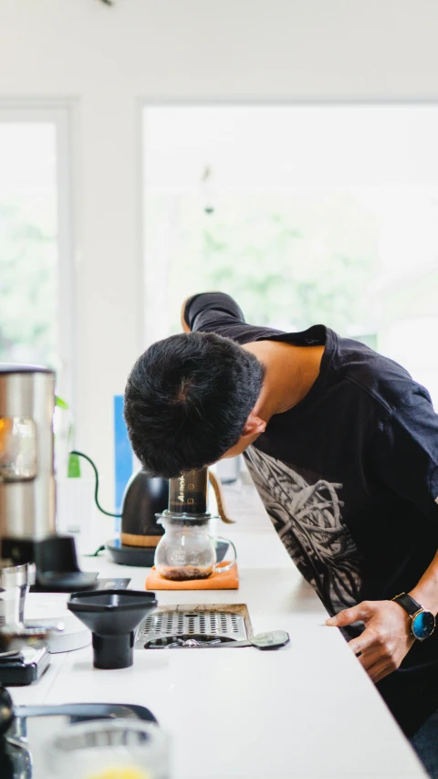 a woman looking down at a grinder in a kitchen