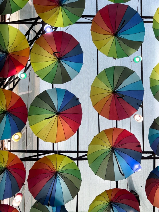 multiple umbrellas are hung up behind a wall