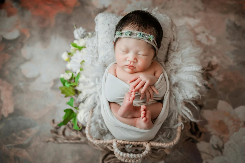 a sleeping baby wrapped in white sits in a basket