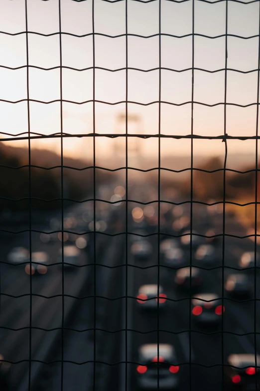 cars in traffic viewed through a screen fence